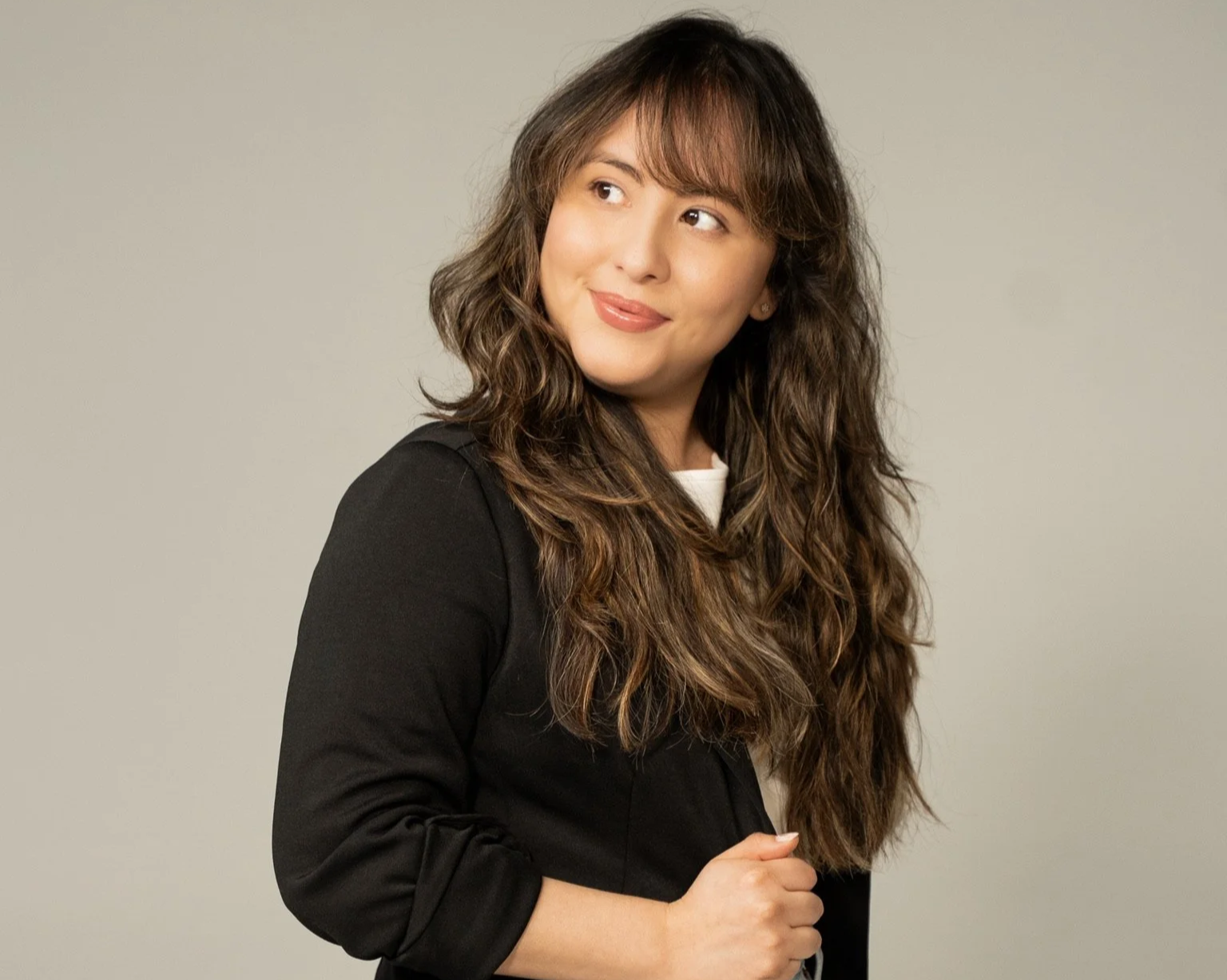 Landscape of a lake with green hills and mountains in the background under a cloudy sky.
