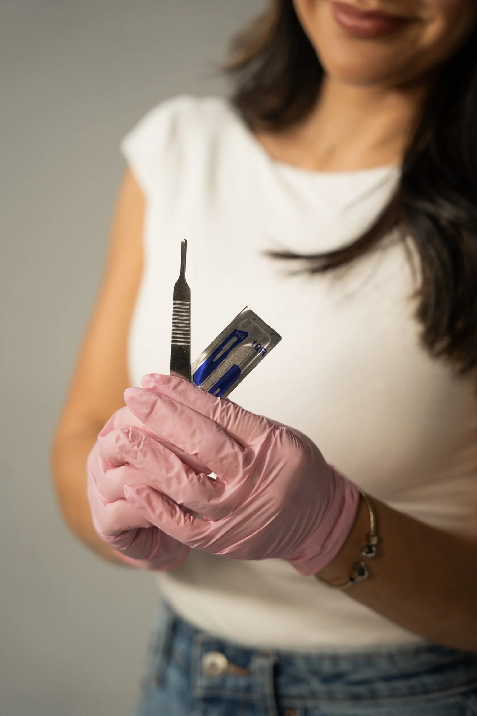A woman with long dark wavy hair wearing a black medical uniform standing with her arms crossed, smiling at the camera.