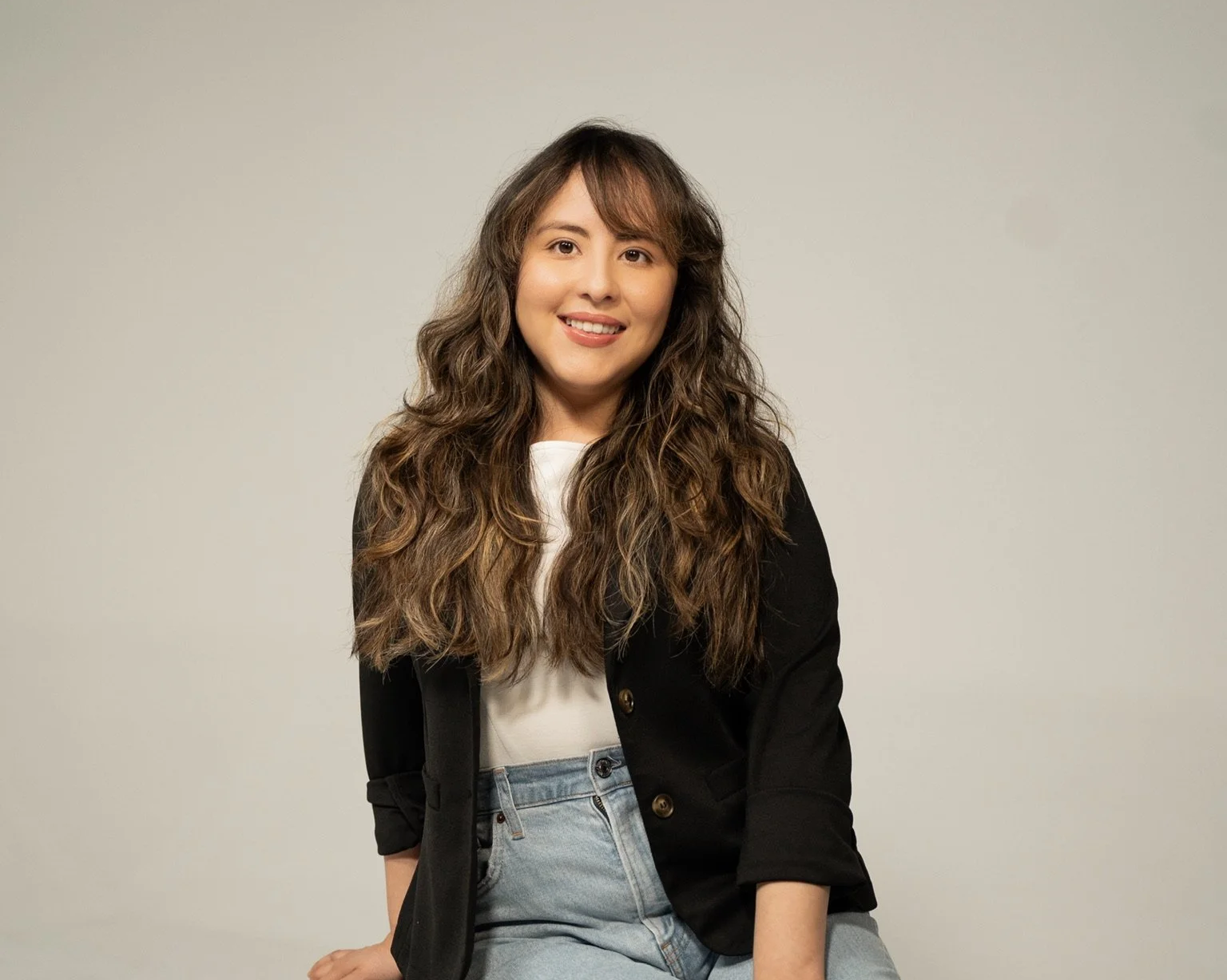 Scenic view of a modern house on a hill with green grass, with snow-capped mountains in the background under a cloudy sky.