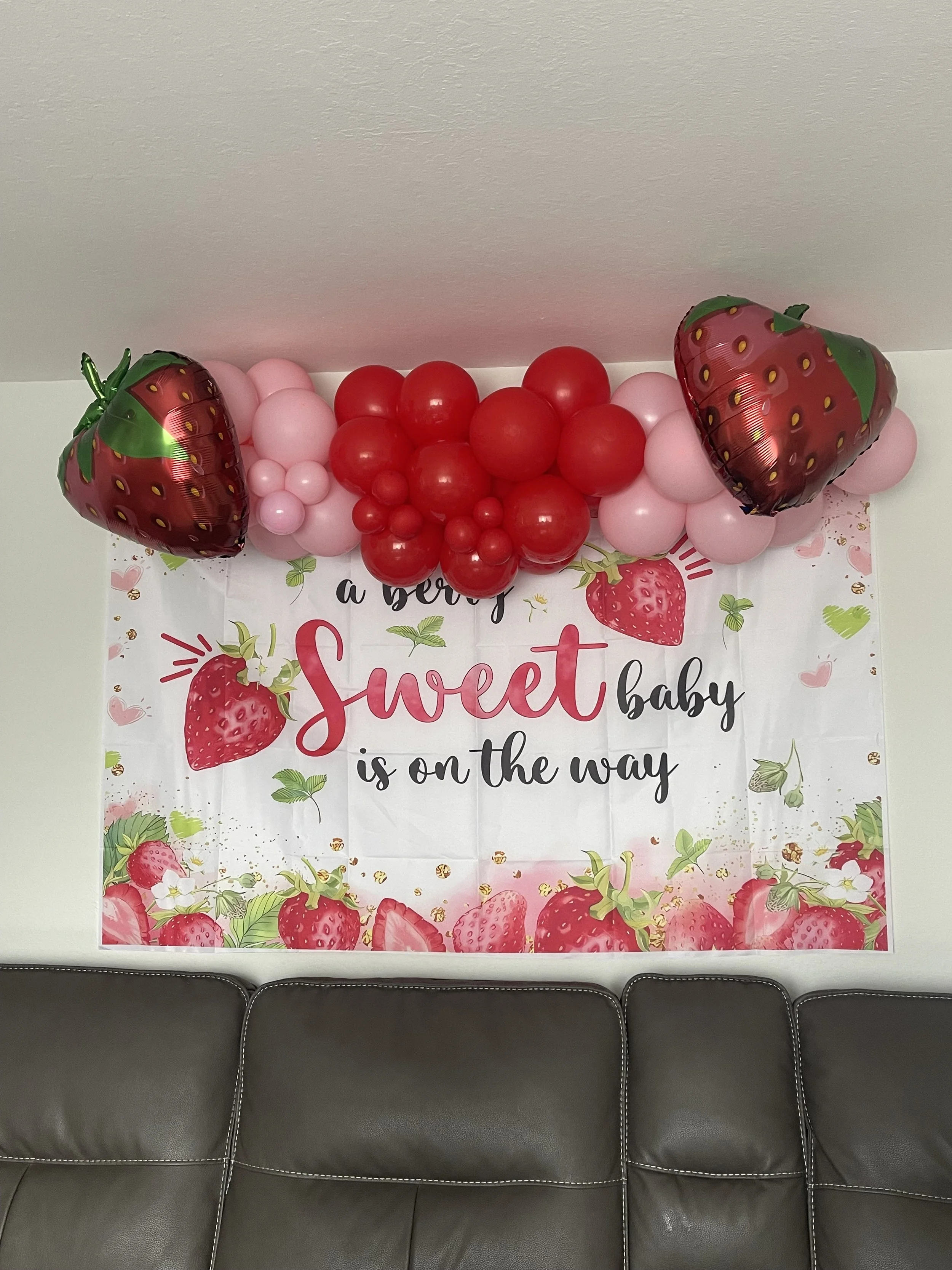 A large outdoor wall covered with white flowers and green leaves, with a partial view of a metal pole on the left side and a grassy area at the bottom.