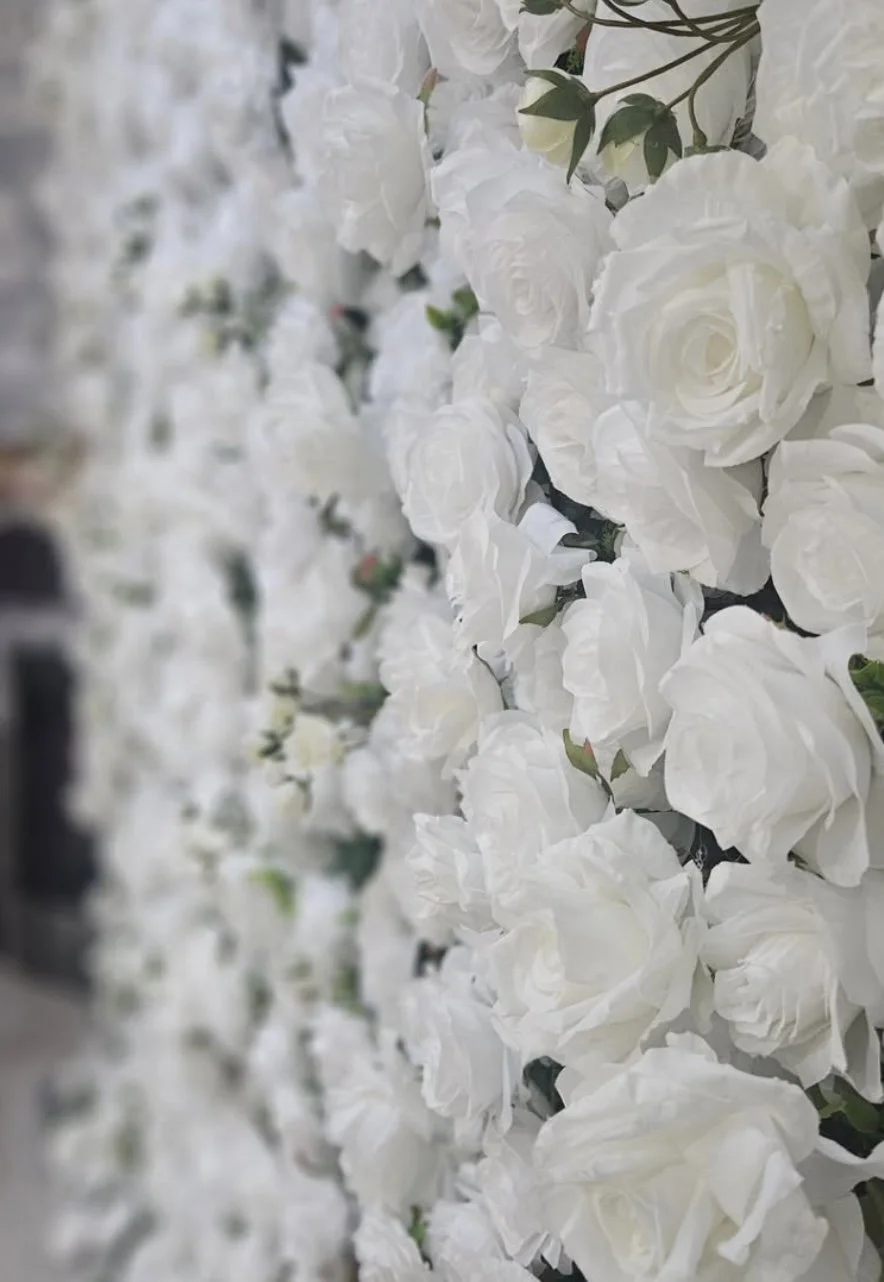 Close-up of a wall decorated with numerous white roses and green leaves
