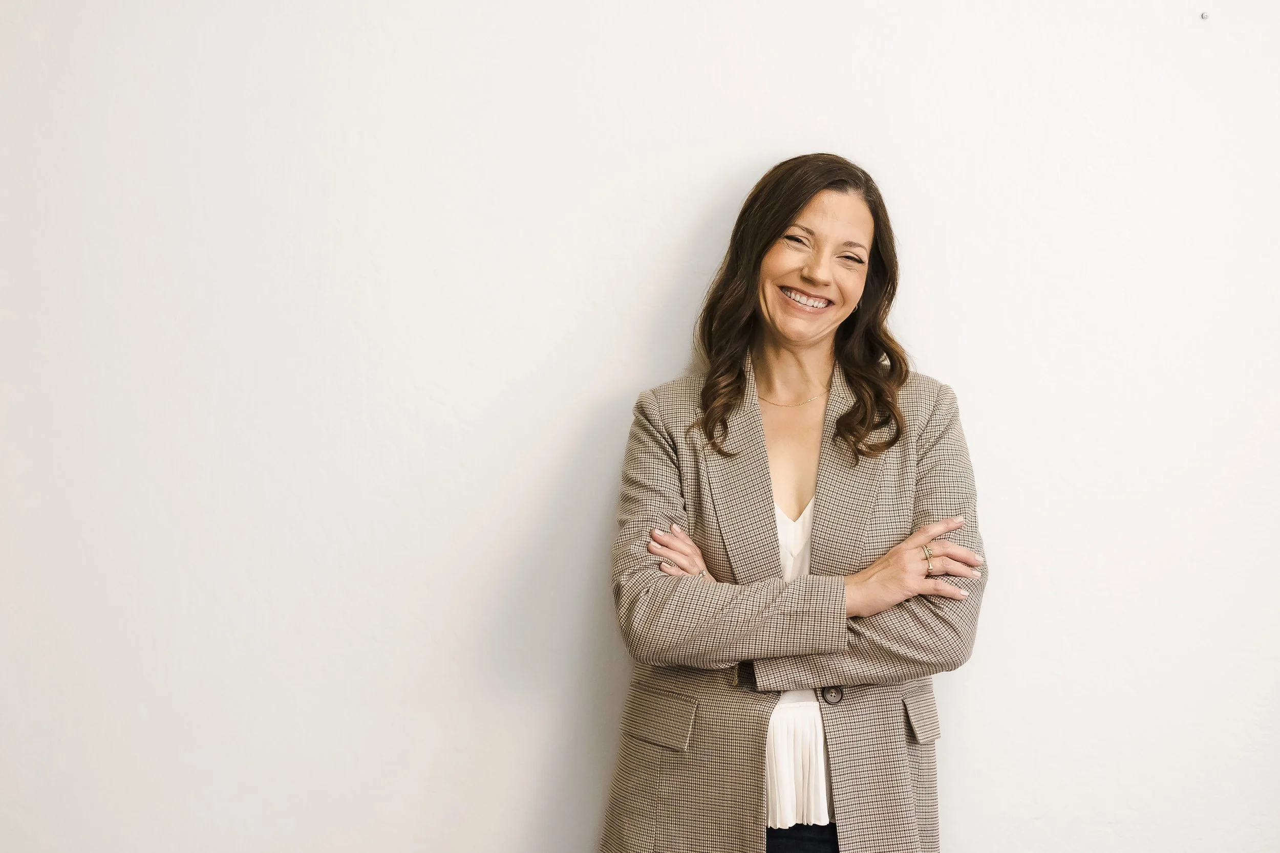 Therapist in a blazer smiling against a white wall