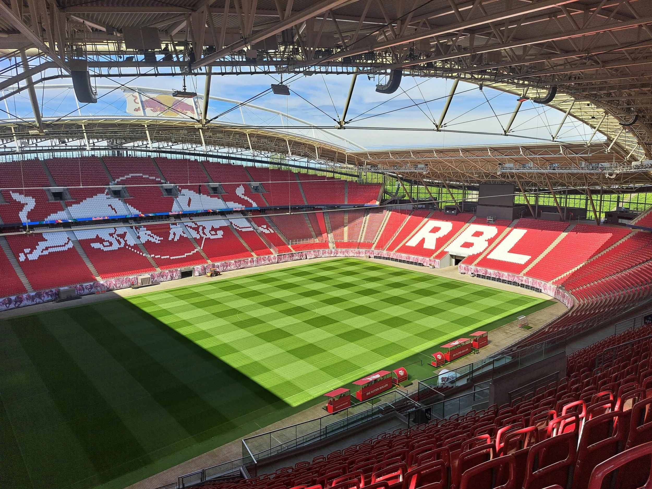Sonnenschein in der leeren Red Bull Arena Leipzig. Der grüne Rasen des Innenraums leuchtet hell.