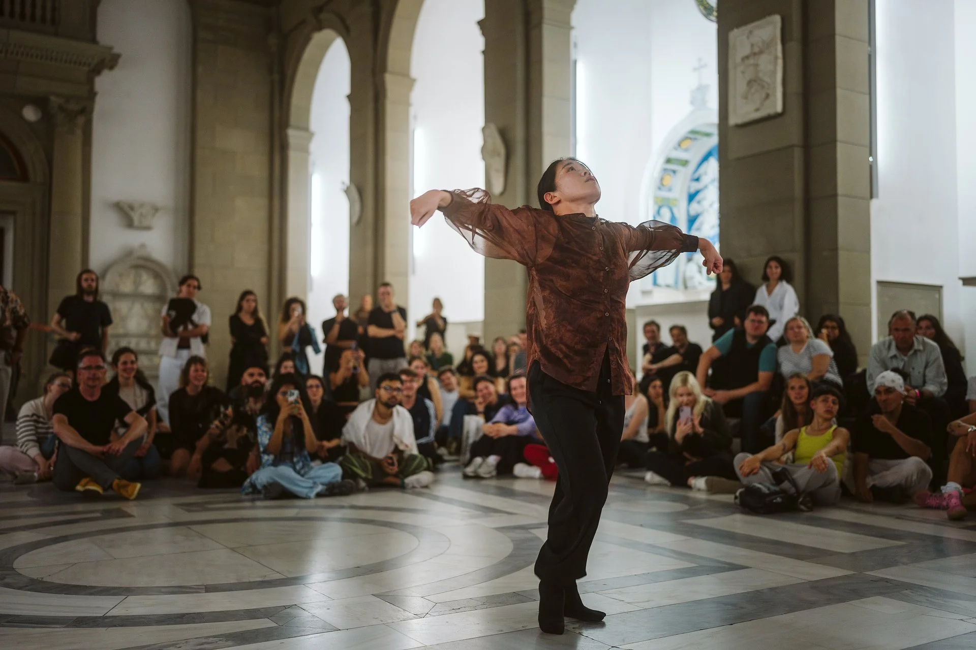 Eine Performerin tanzt im Bodemuseum. Das Publikum sitzt auf dem Marmorboden um sie herum.
