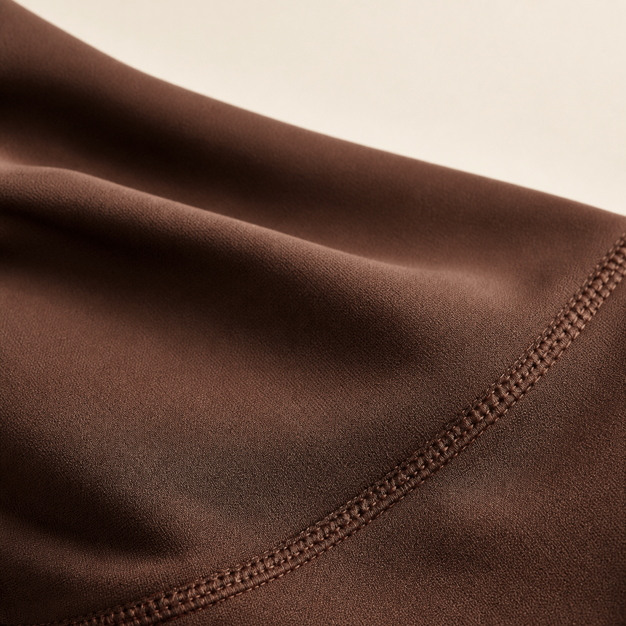 Close-up of brown fabric with visible stitching along the edge.