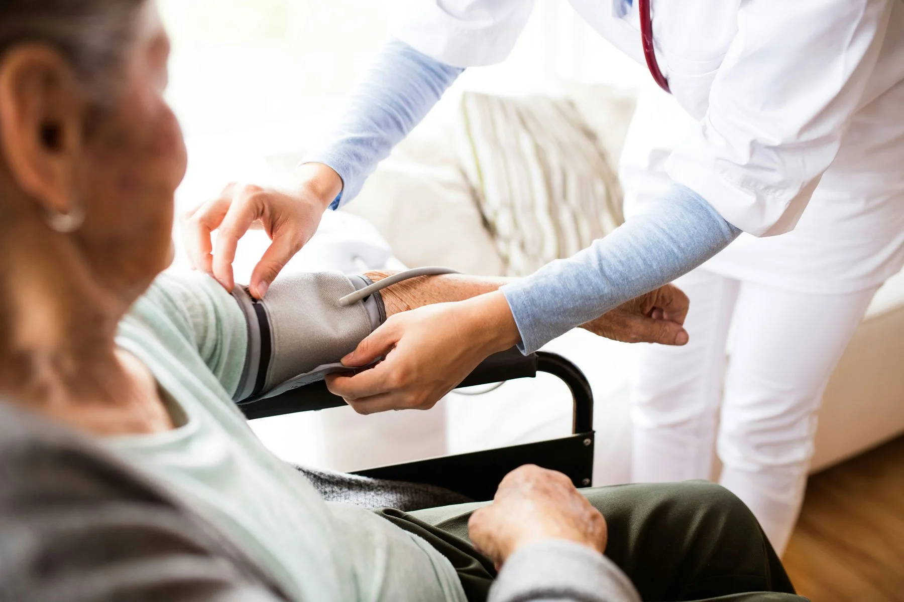 A senior at-home caregiver checks an older adult's blood pressure as part of in-home senior care services.
