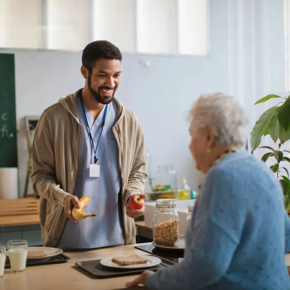 A memory care caregiver serves lunch to an older adult during an in-home care visit.