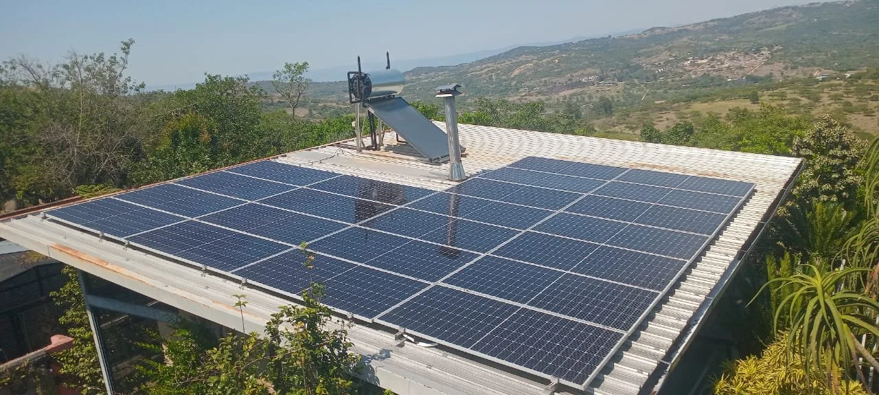 Solar panels installed on the roof of a building with a scenic view of hills and green landscape in the background.