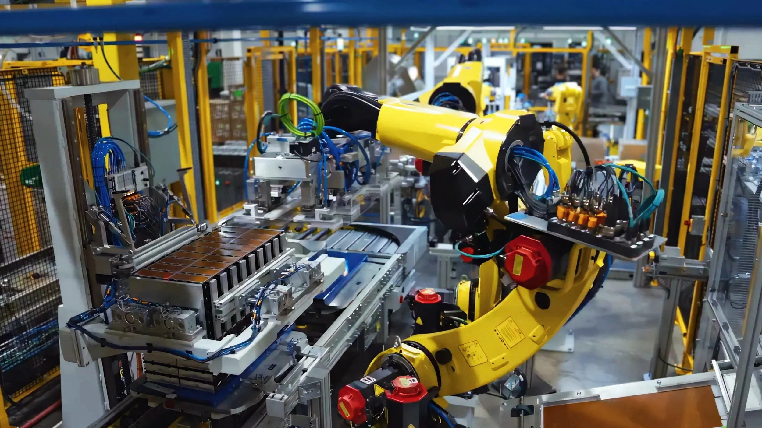A yellow robotic arm operating on an automated assembly line in a manufacturing plant.