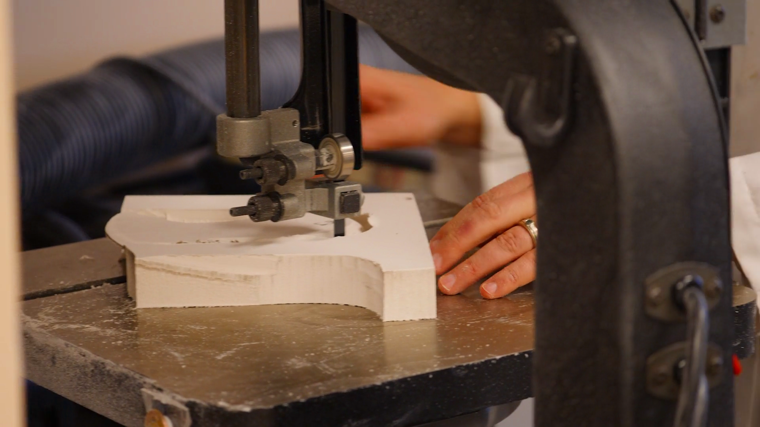 Person operating a bandsaw to cut a piece of wood.