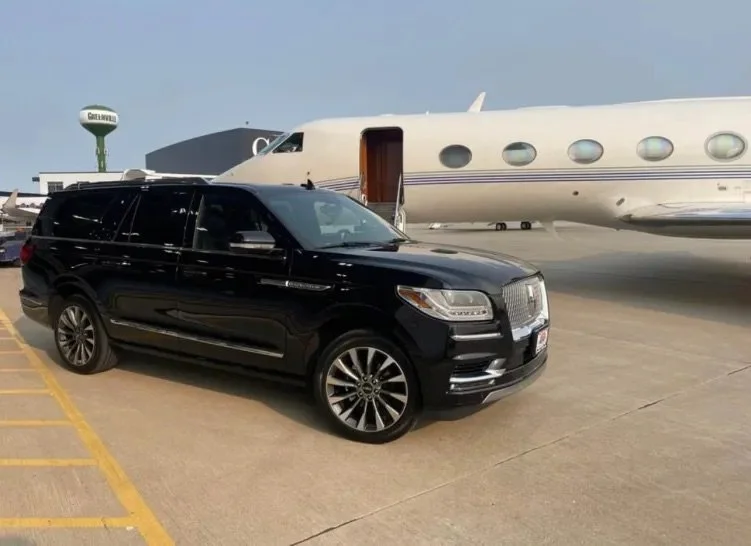 Black SUV parked on tarmac near private jet airplane.