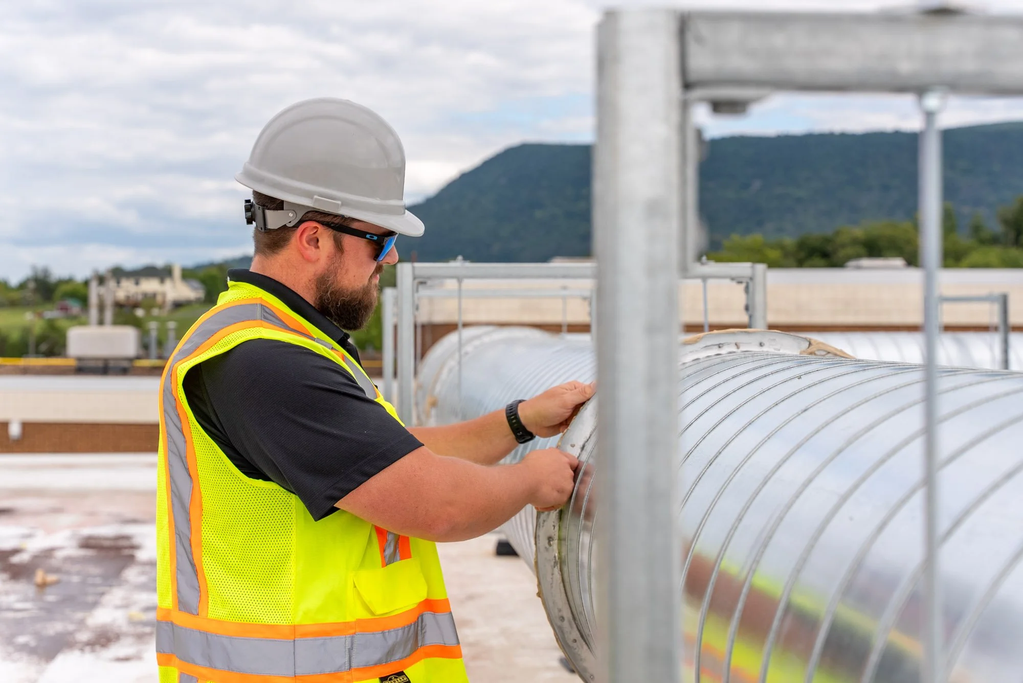 A Blauch Brothers technician checks the fit of a custom ductwork joint on the roof of Sandy Hook Elementary School, part of the field team's solution to a fit issue during the HVAC upgrade.
