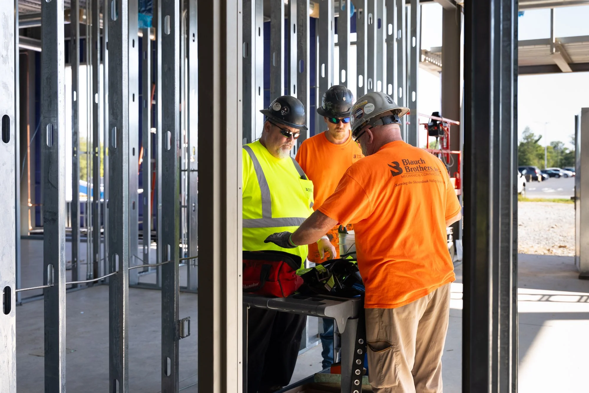 Three Blauch Brothers crew members talk through the next task around a tool table inside the framed Daikin Applied office building in Verona, Virginia.
