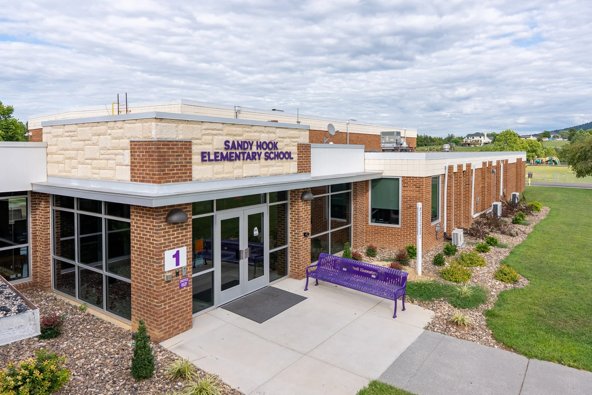 The front entrance of Sandy Hook Elementary School in Strasburg, Virginia, featuring the school's purple bench and main doors.