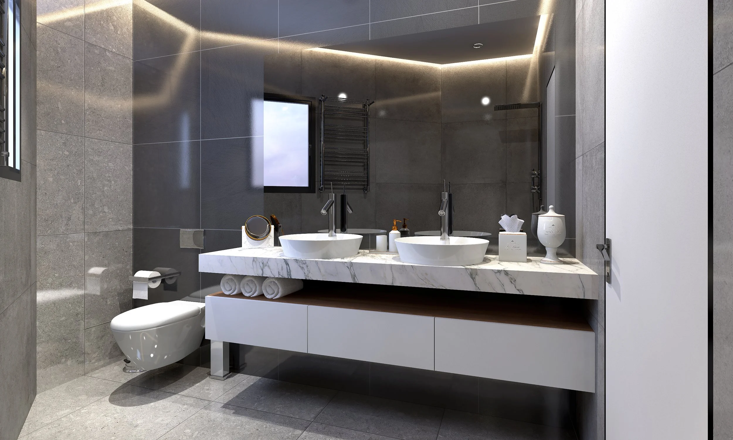 Modern bathroom with dual sinks, large mirror, white marble countertop, and gray tiled walls and floor. Toilet with toilet paper, small mirror, tissue box, soap, and decorative vase on the countertop. Window with sky view, towel rack, and ceiling lighting.