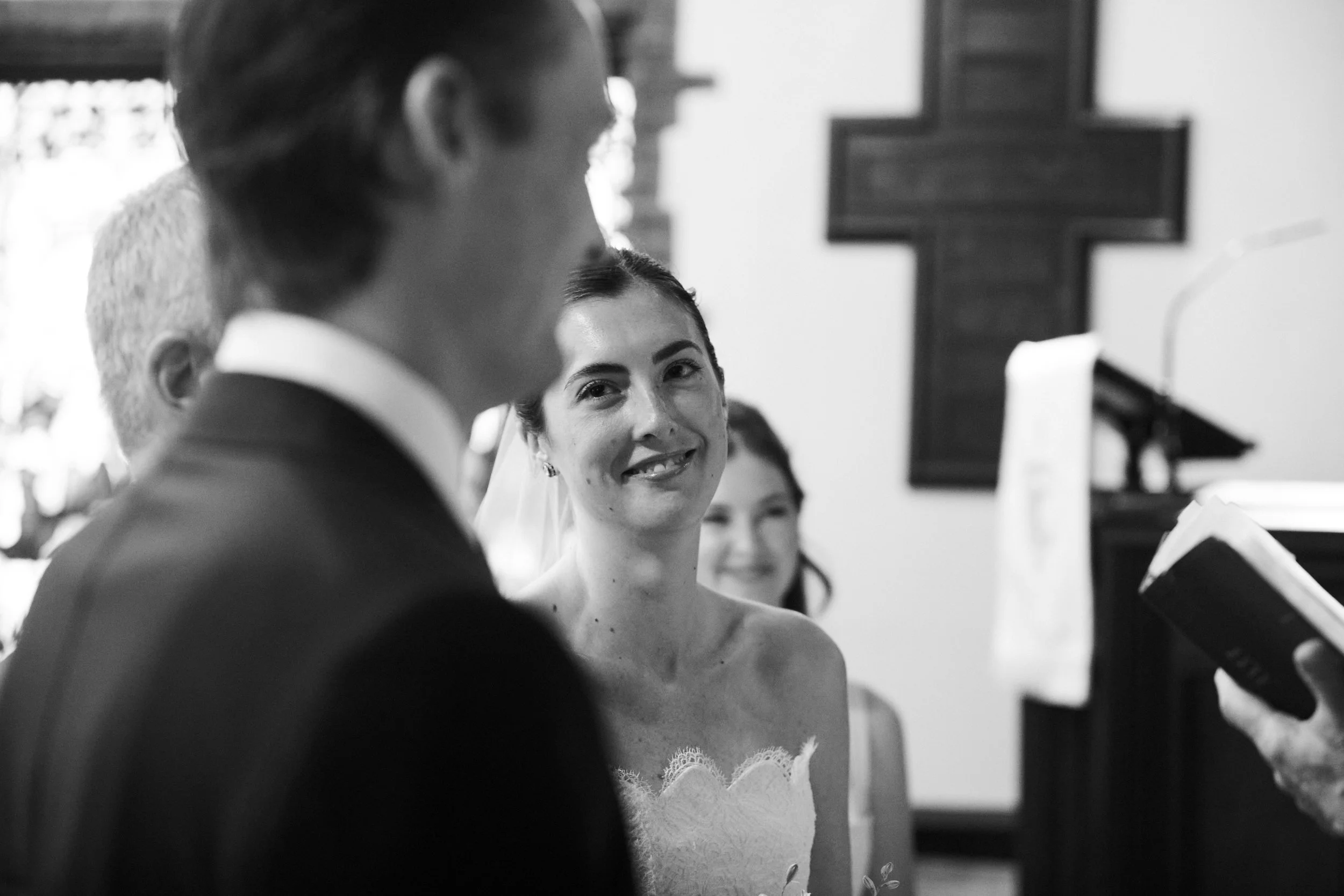 A bride smiling at the groom during their wedding ceremony inside a church.