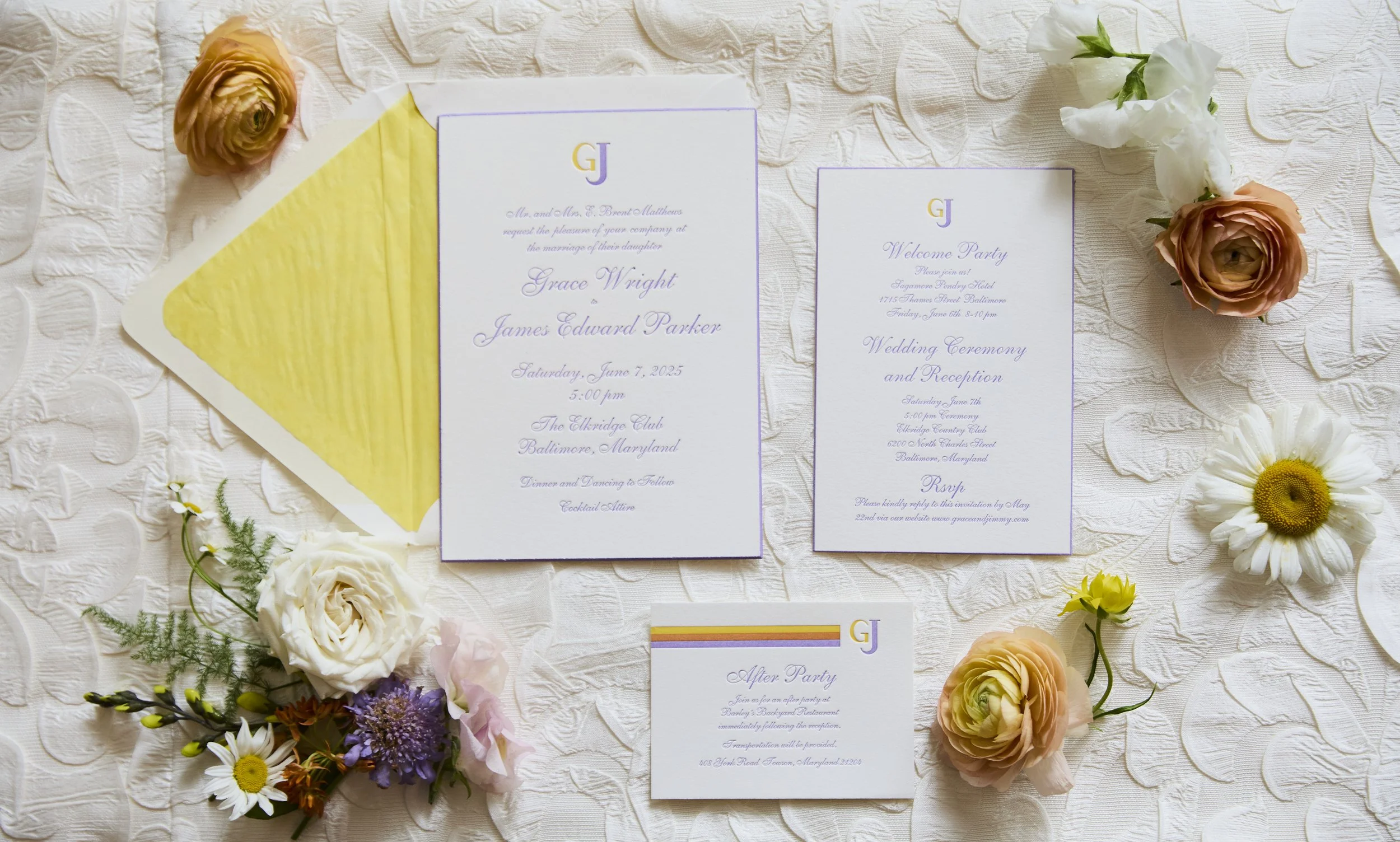 Wedding invitation suite with flowers on a textured white tablecloth. Includes a main invite, two additional cards, a yellow envelope, and floral arrangements with roses, daisies, and greenery.
