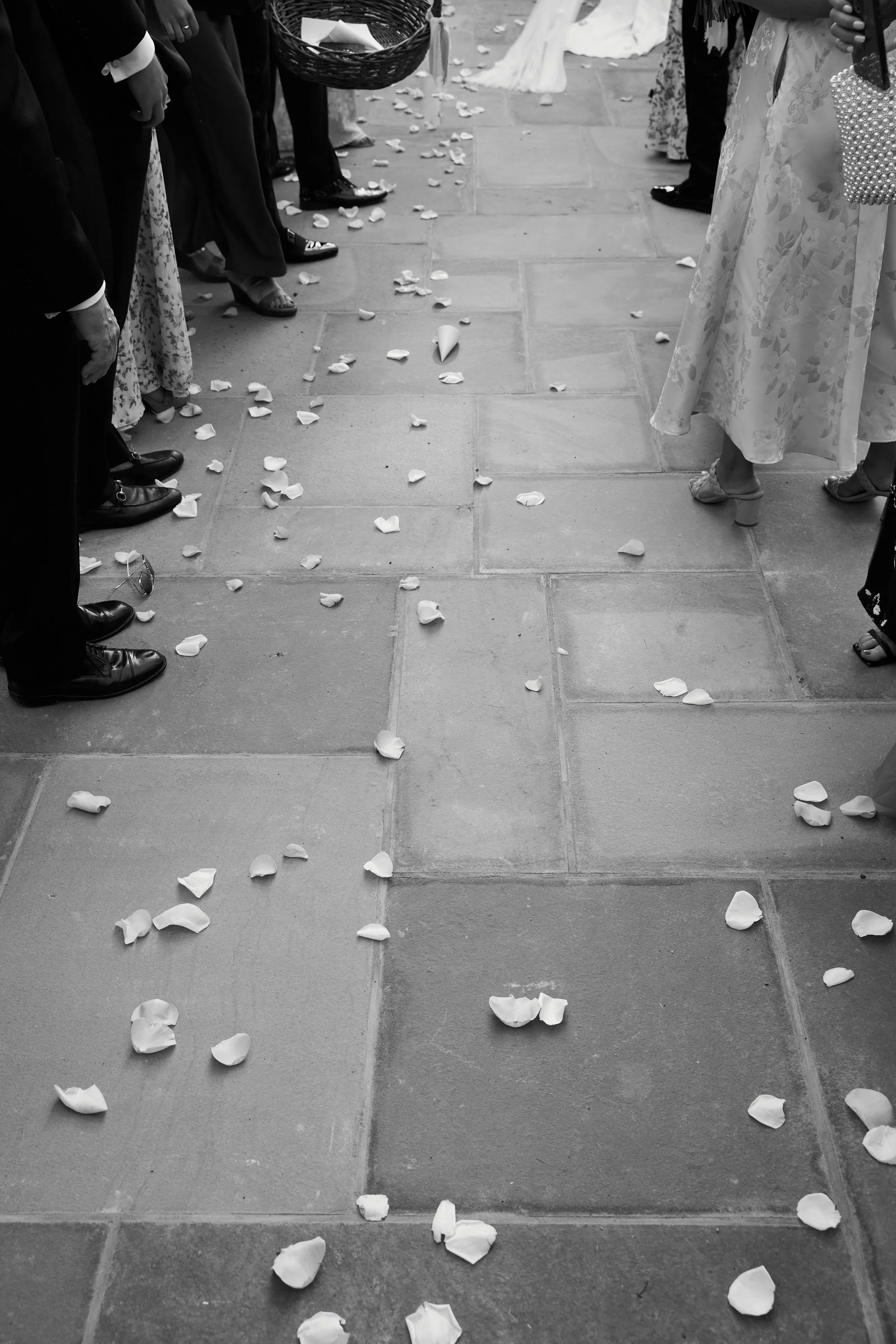 Petals scattered on the floor at a wedding ceremony, with guests standing around.