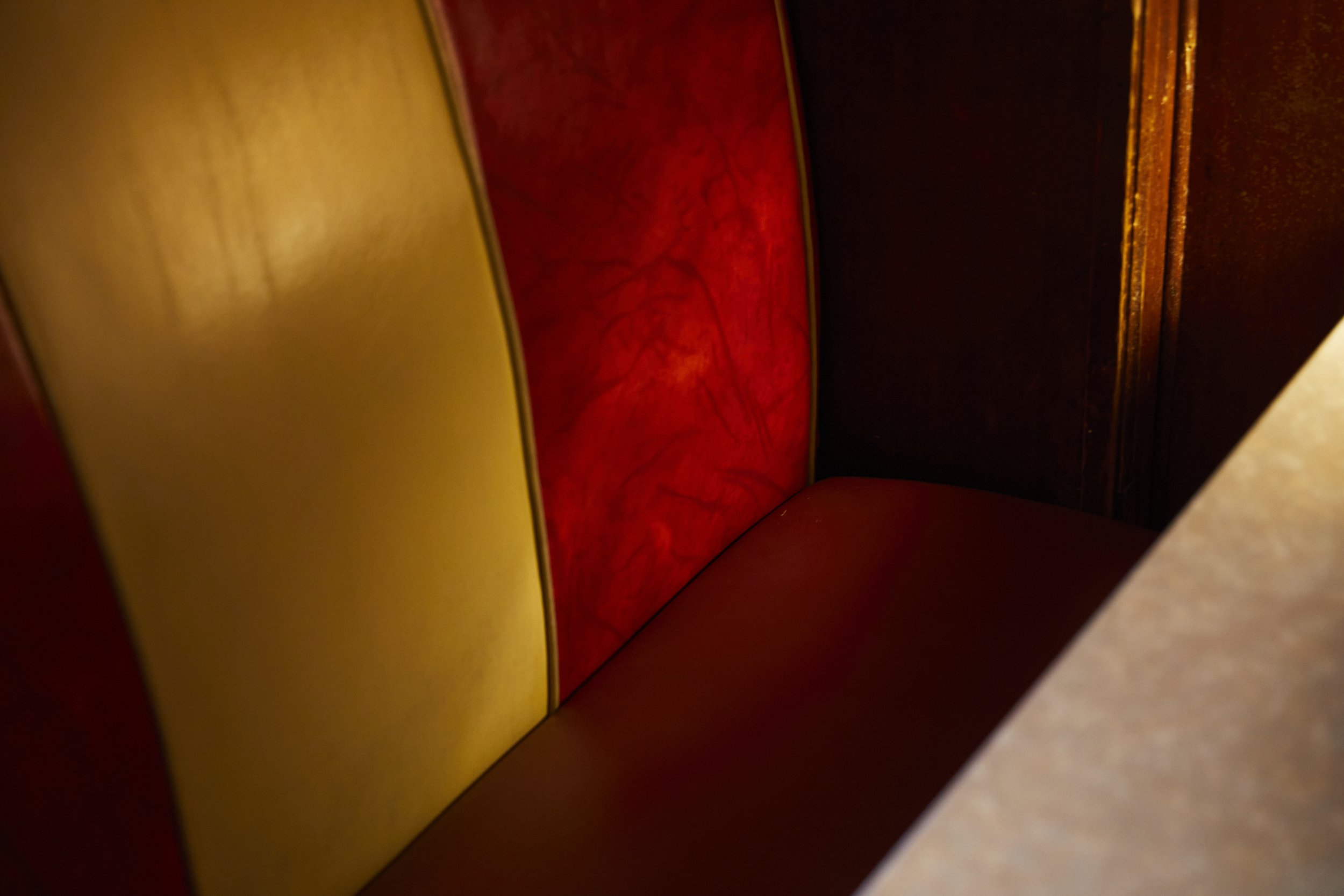 Close-up of a vintage booth seat with yellow, red, and dark brown paneling.