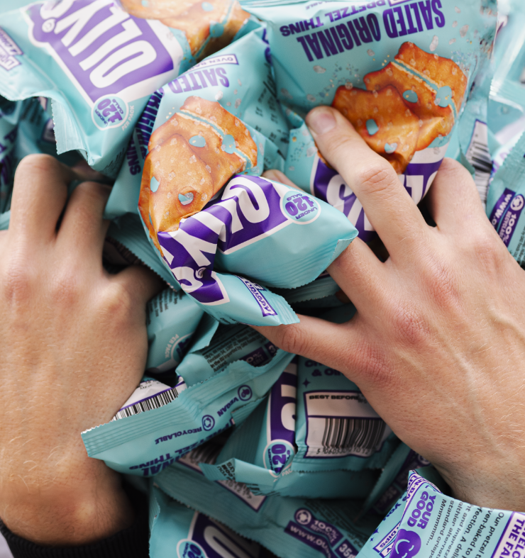 Hands holding multiple blue packages of salted original flavored potato chips.