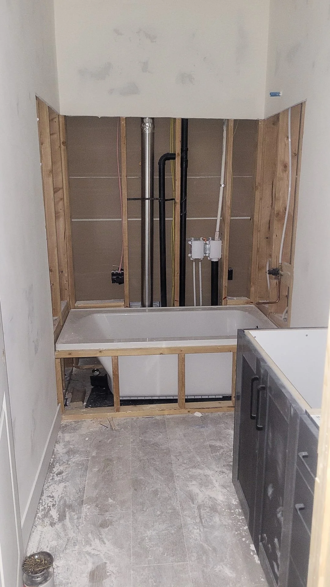 Bathroom under renovation with a bathtub, exposed plumbing, and construction materials.