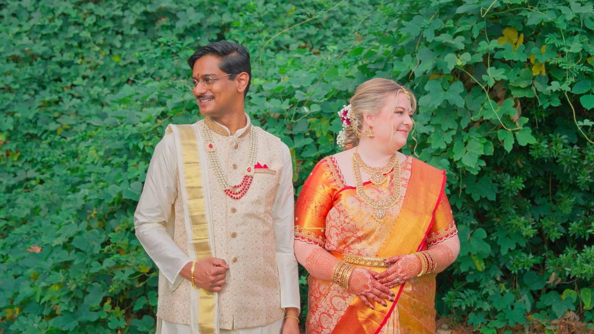 A couple in wedding attire sharing an intimate moment outdoors at sunset, with trees in the background.
