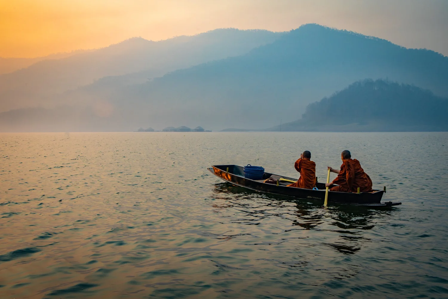 A wooden boat on a still lake beneath mist-covered hills