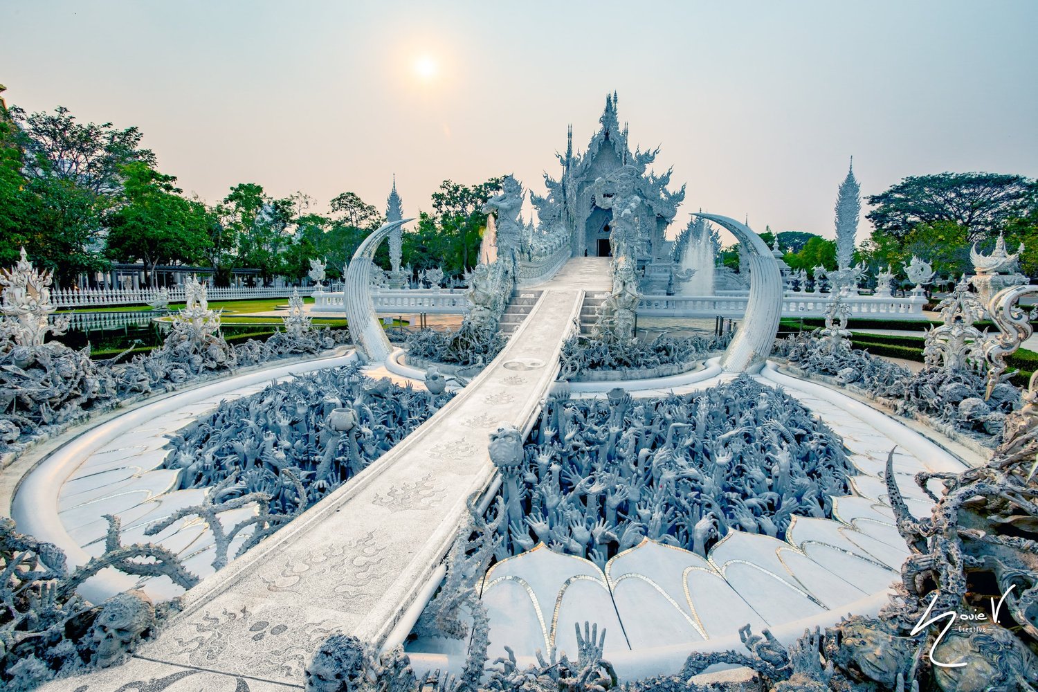 An ornate white temple and bridge under a hazy sky