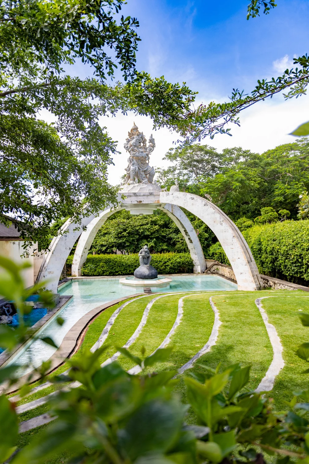 A sculptural garden fountain beneath a canopy of trees