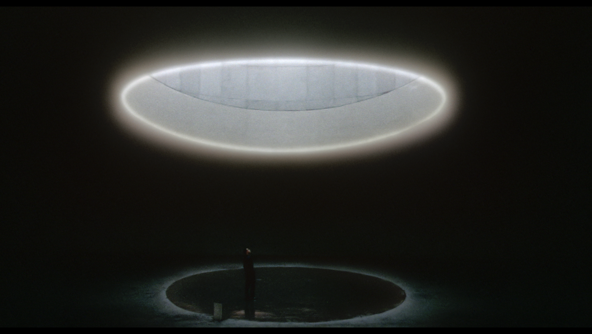 Close-up of a modern recessed ceiling light fixture with a glowing ring of light and a reflective surface.