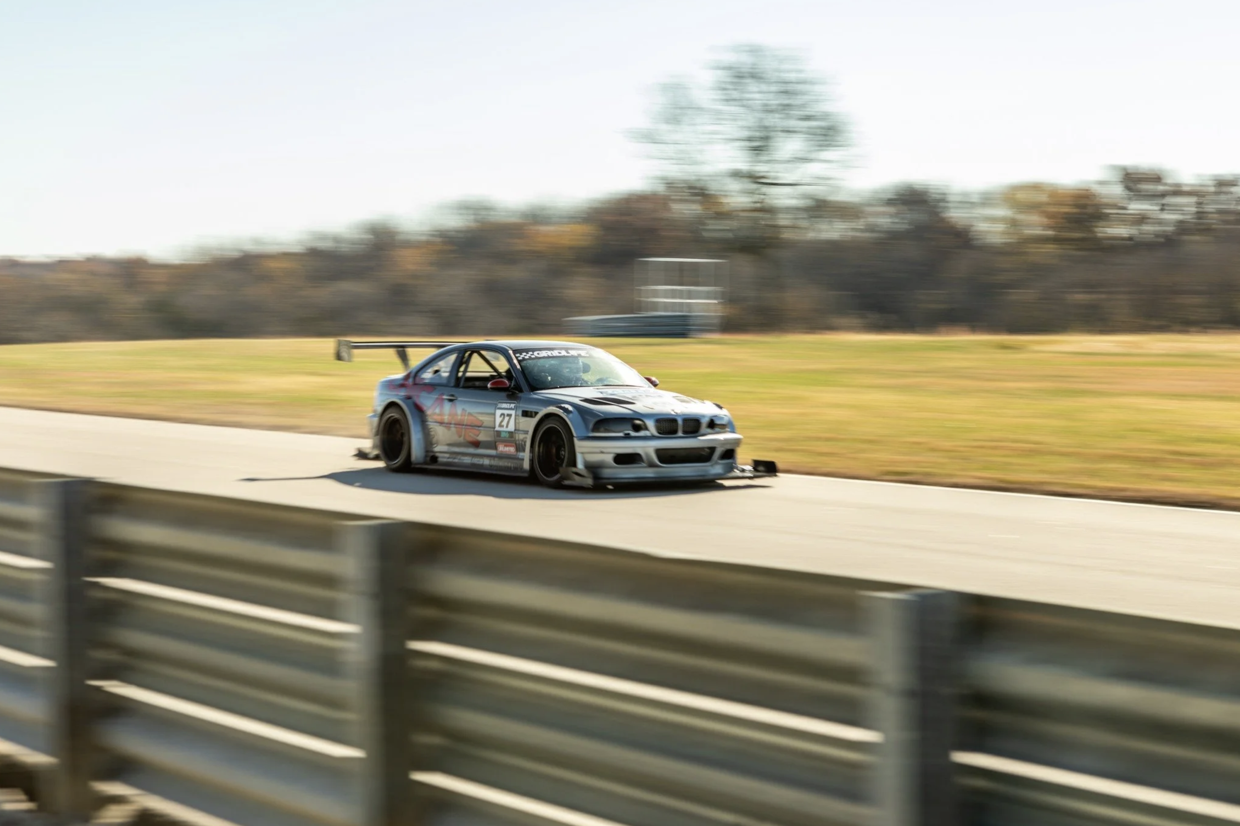 A racing car on a track, with a silver body and black accents, moving at high speed during a race.