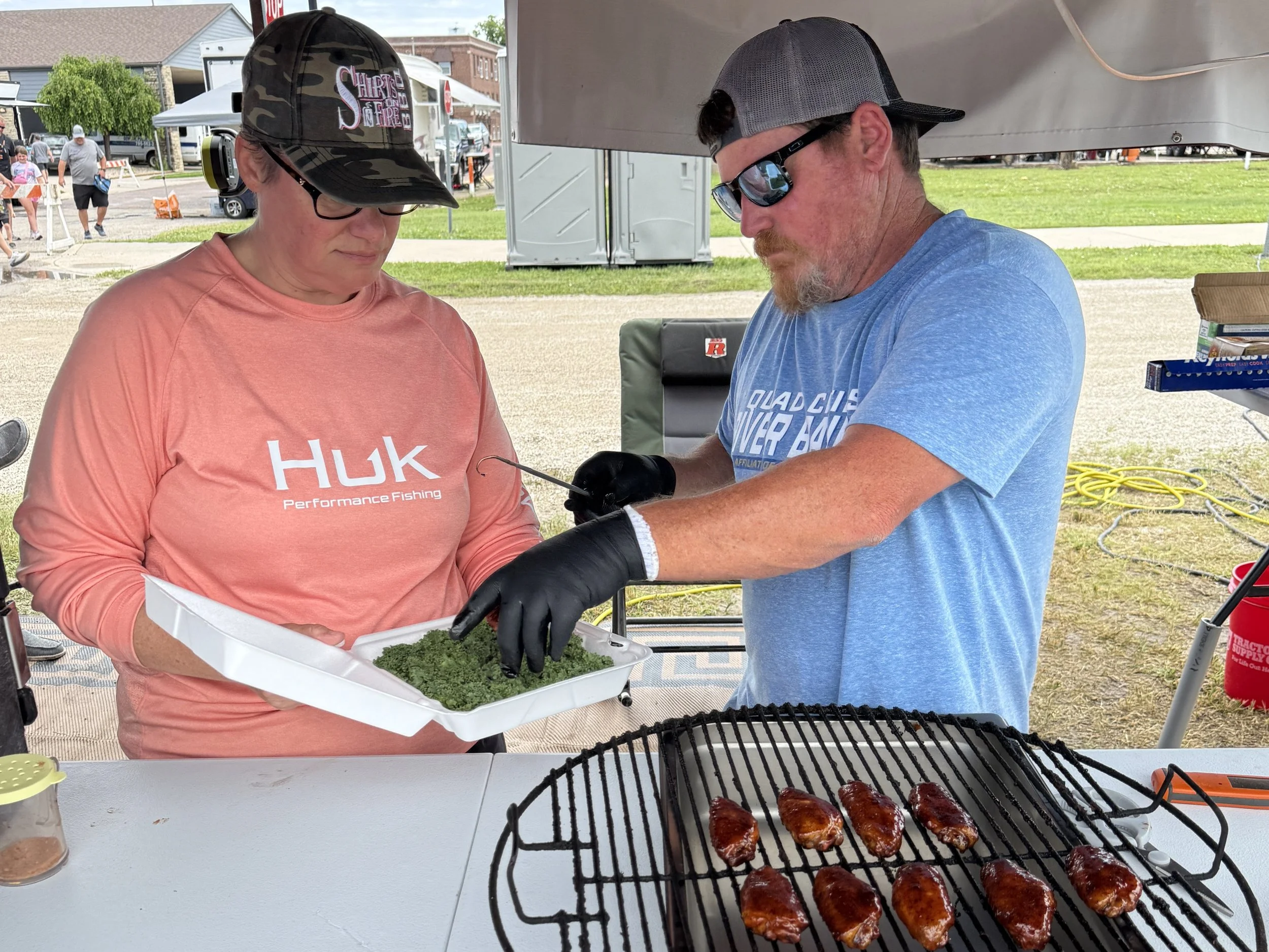 John placing competition wings into the turn-in box that Stacy is holding.