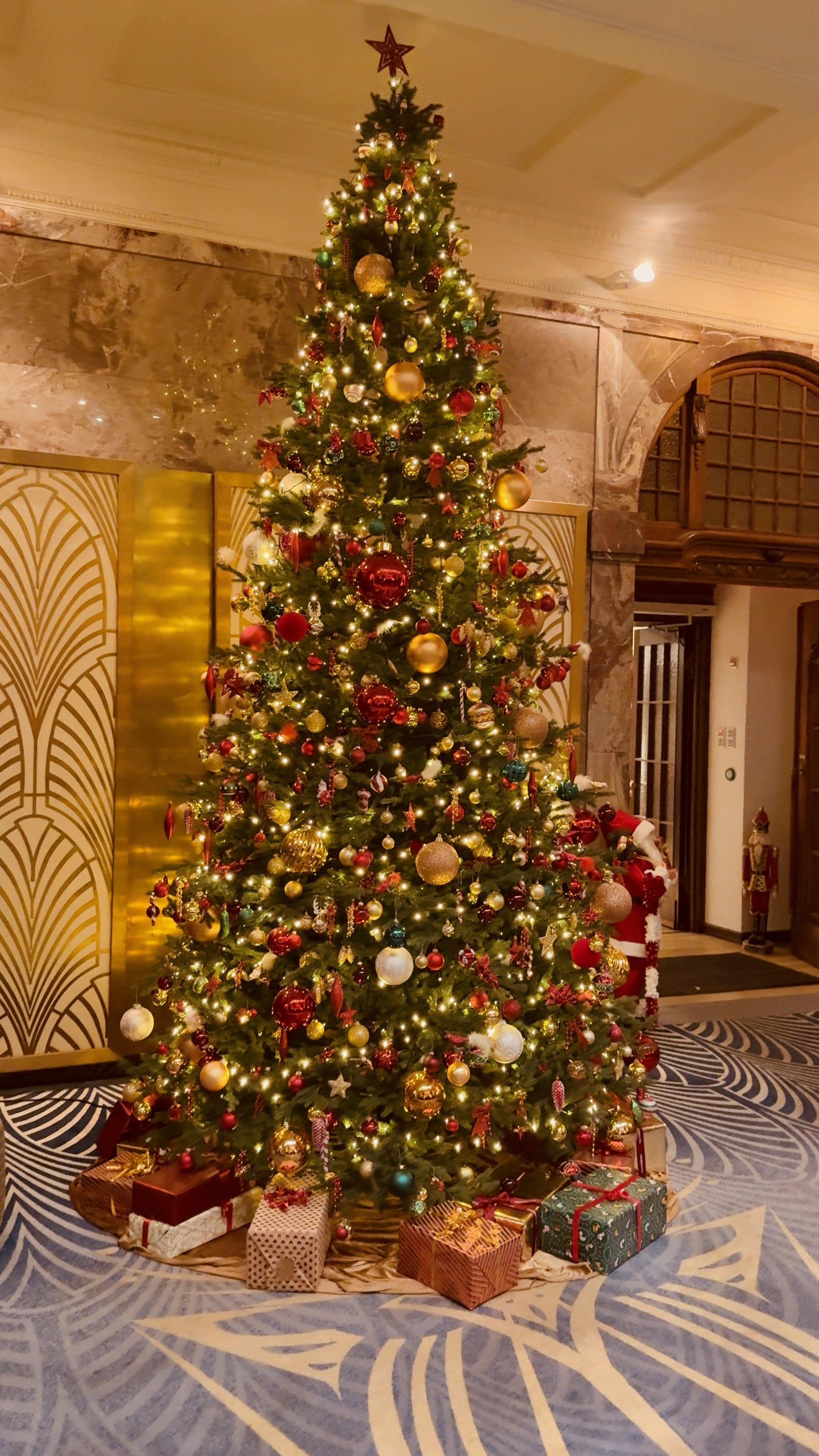 Großer festlich geschmückter Weihnachtsbaum mit Lichtern und Geschenken.