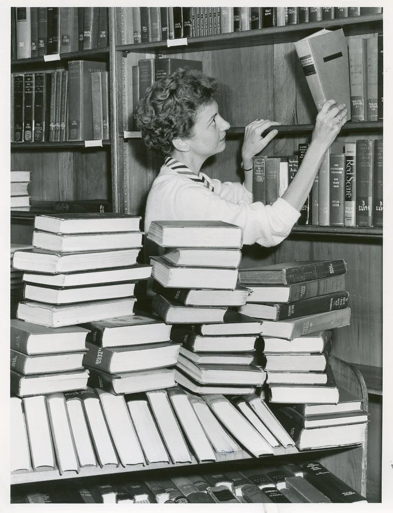 black and white image of librarian shelving books