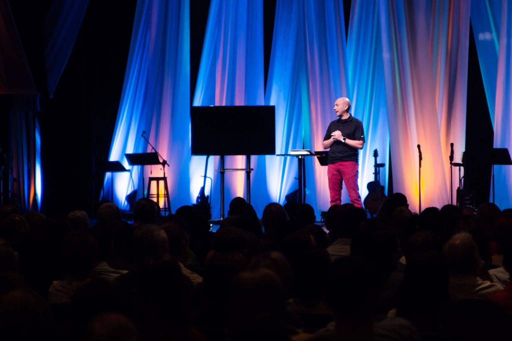John D Harney featured Keynote Speaker on a stage with a full audience