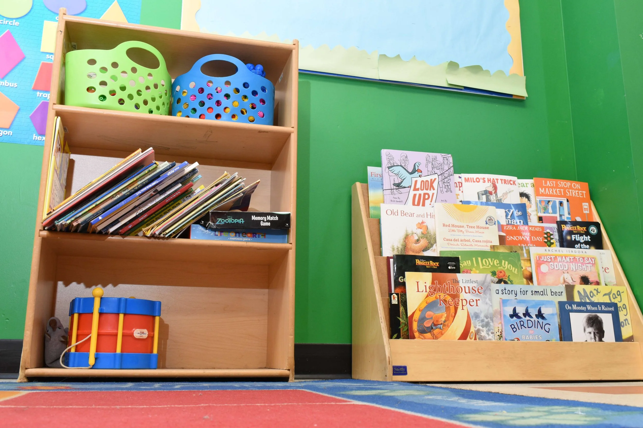 Bookshelf with children's books and toys in a classroom.