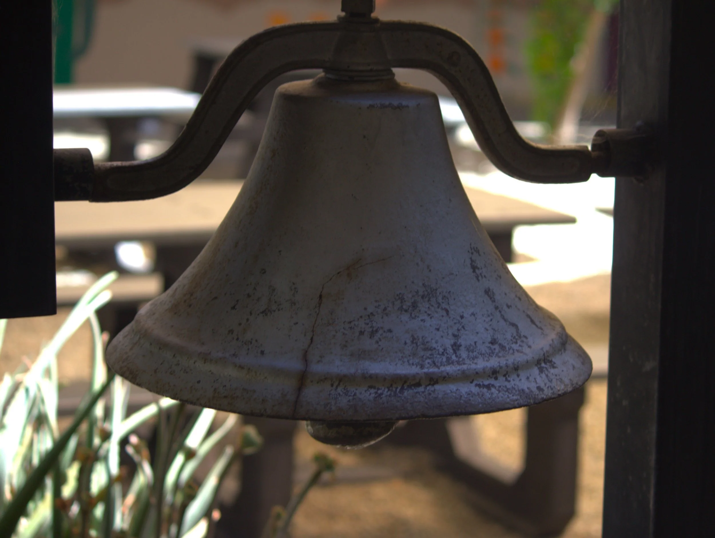 A large bell hanging in the front courtyard at Odyssey.