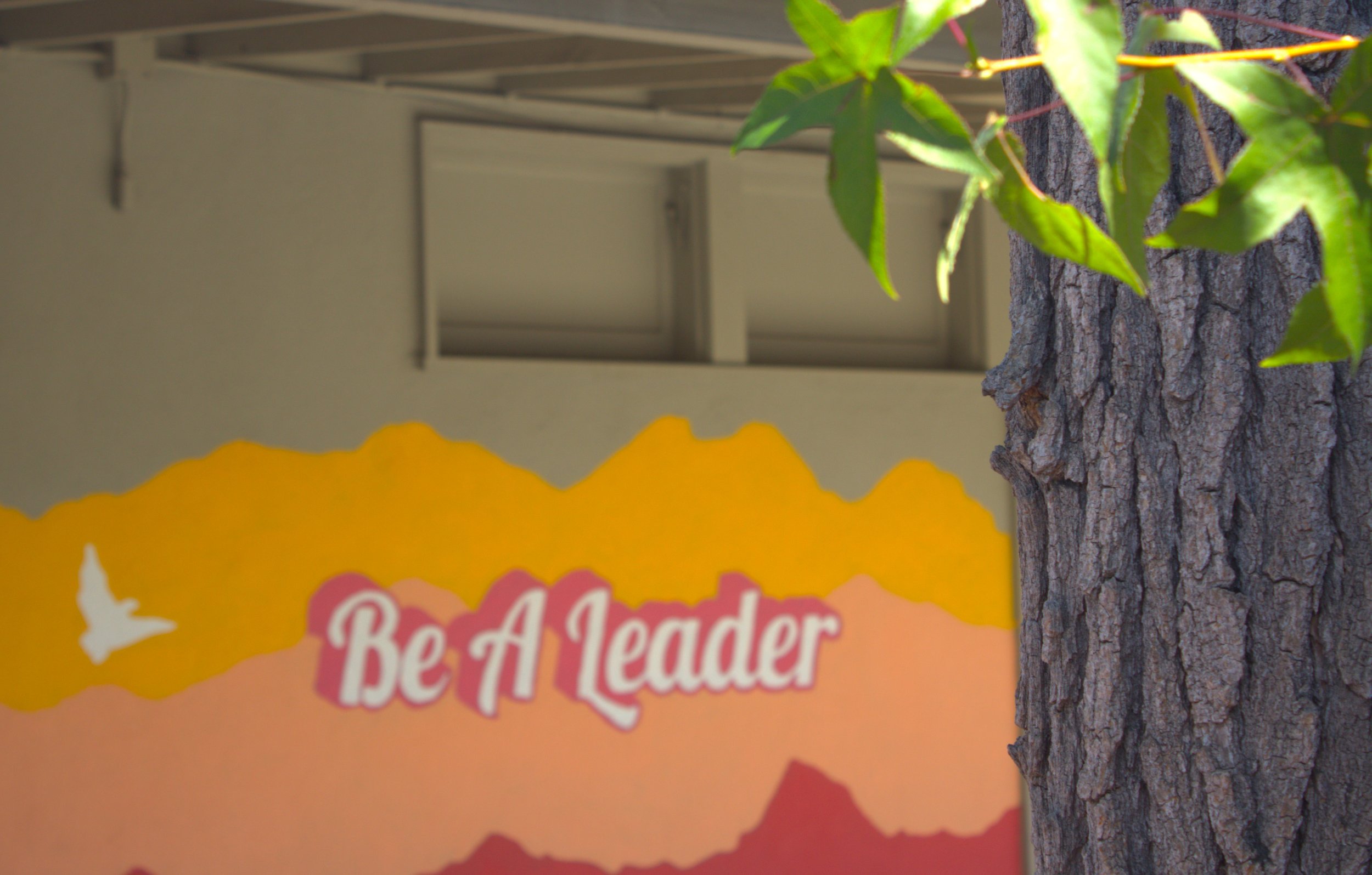 A colorful yellow, orange and red mural reading "Be A Leader"