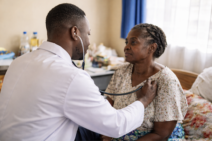 A doctor examining an elderly woman in a hospital or clinic room.