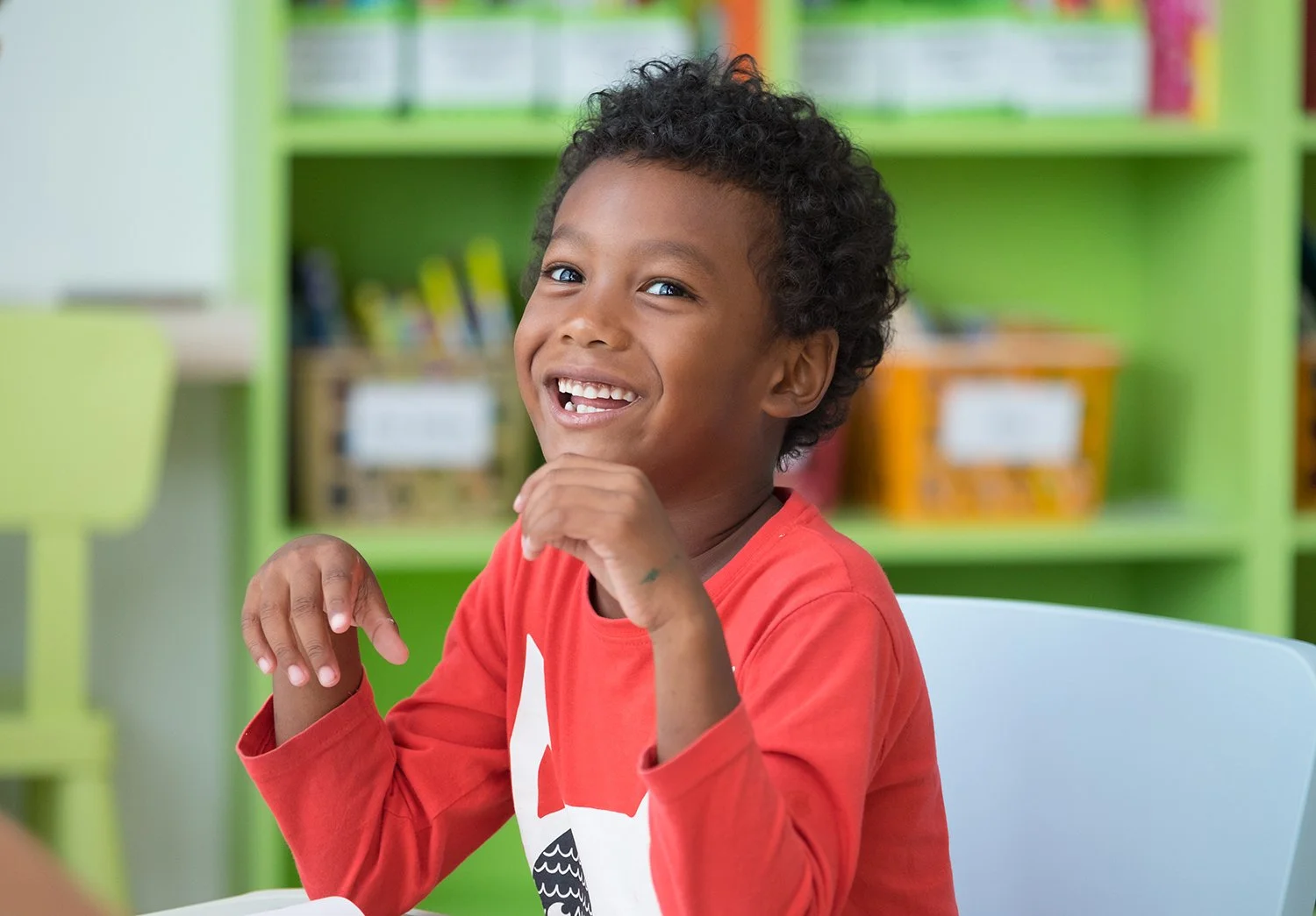 Young boy smiling and sitting at a table during speech therapy for gestalt language processing in Las Vegas, NV