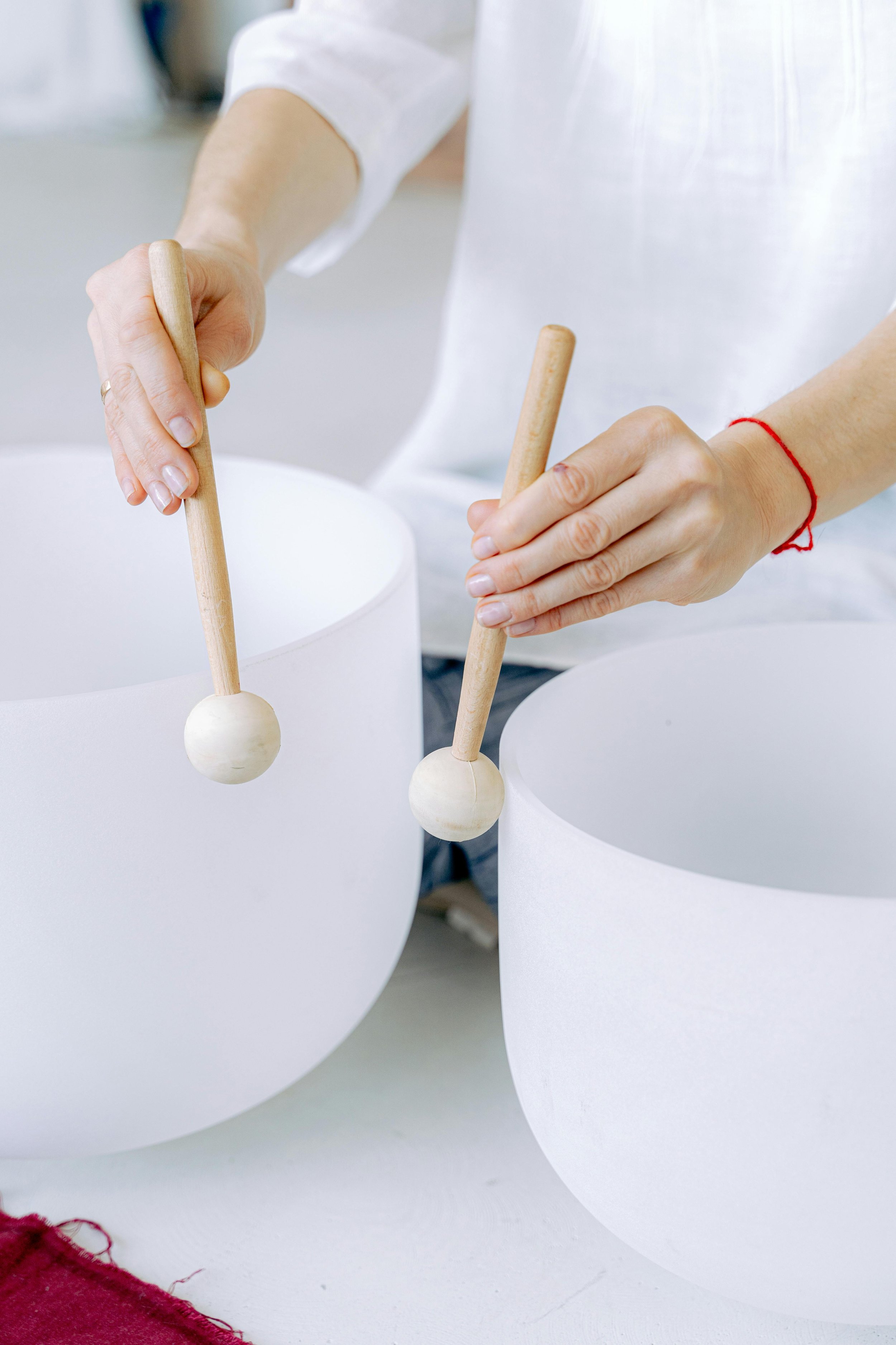 Person playing crystal singing bowls with wooden mallets.