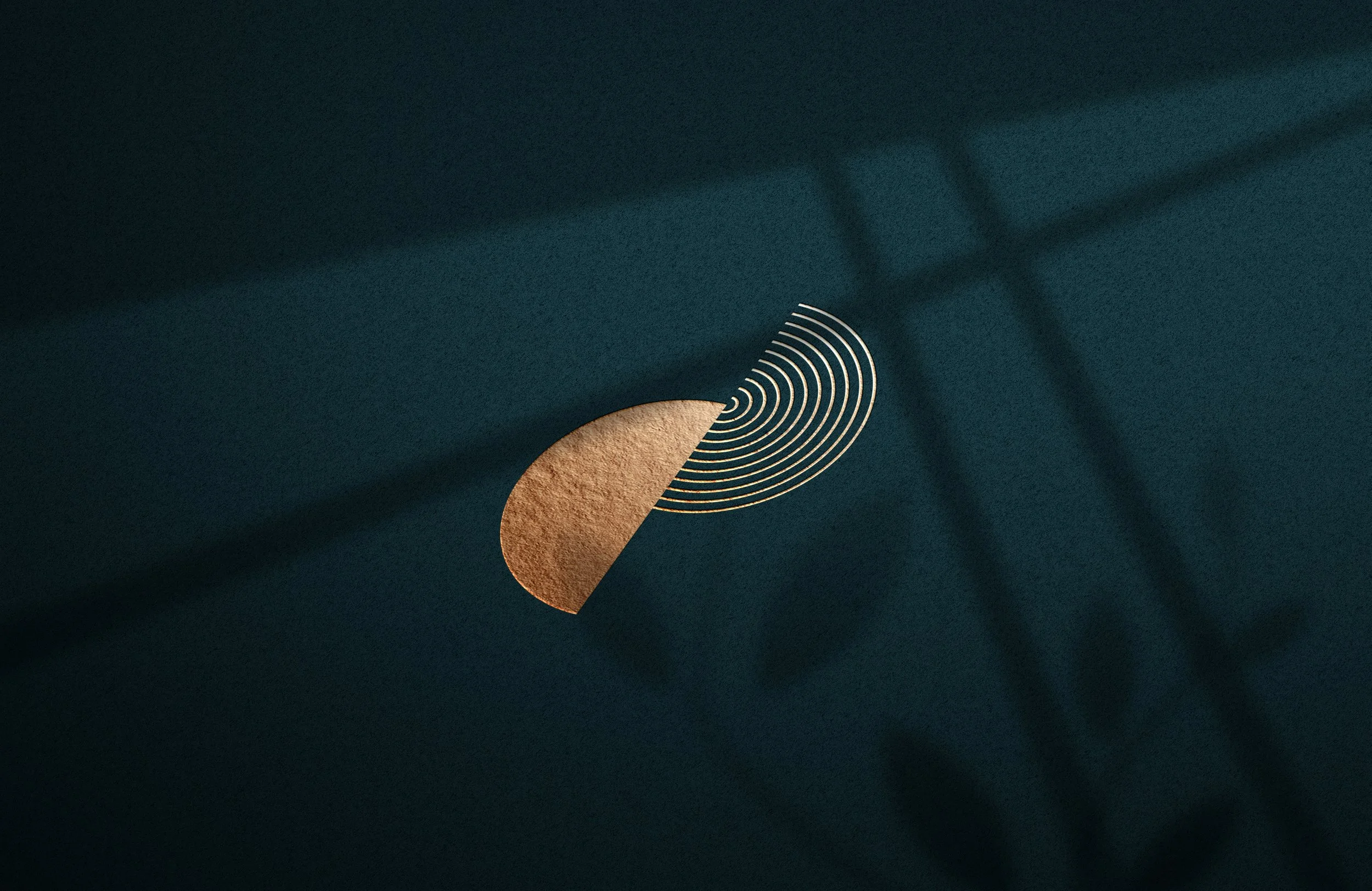 A dark surface with a partial circular gold pattern and white concentric semi-circles, with shadows cast on the surface.