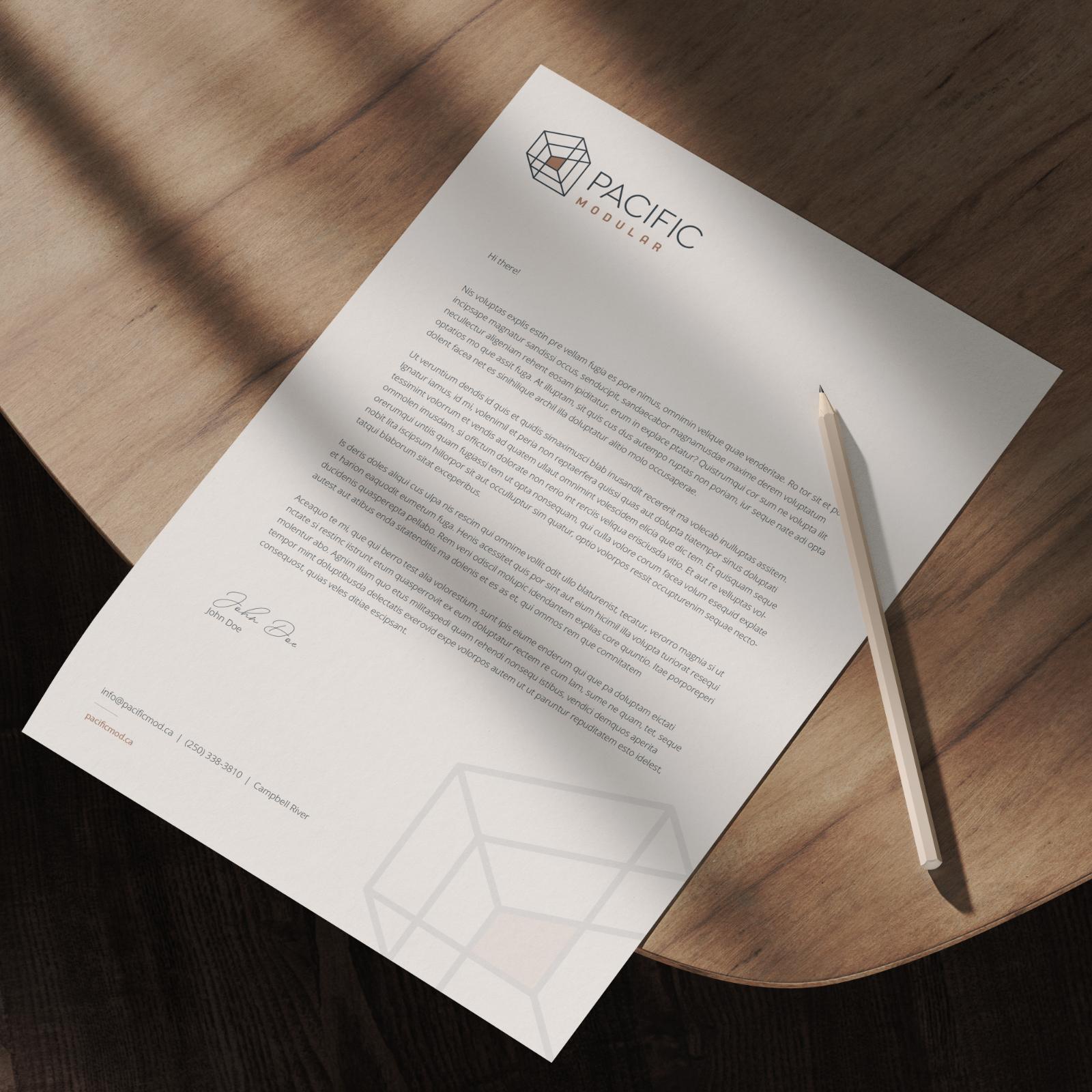 A printed letter on a wooden desk with a logo and the words 'Pacific Modular', a pen placed on the upper right side of the letter, and a subtle geometric pattern at the bottom
