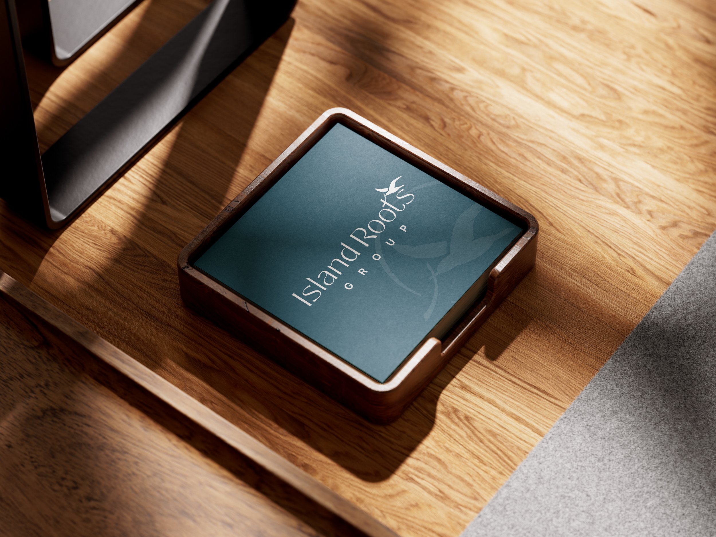 A tablet displaying the Island Roots Group logo on a wooden tray, placed on a wooden table with sunlight casting shadows.