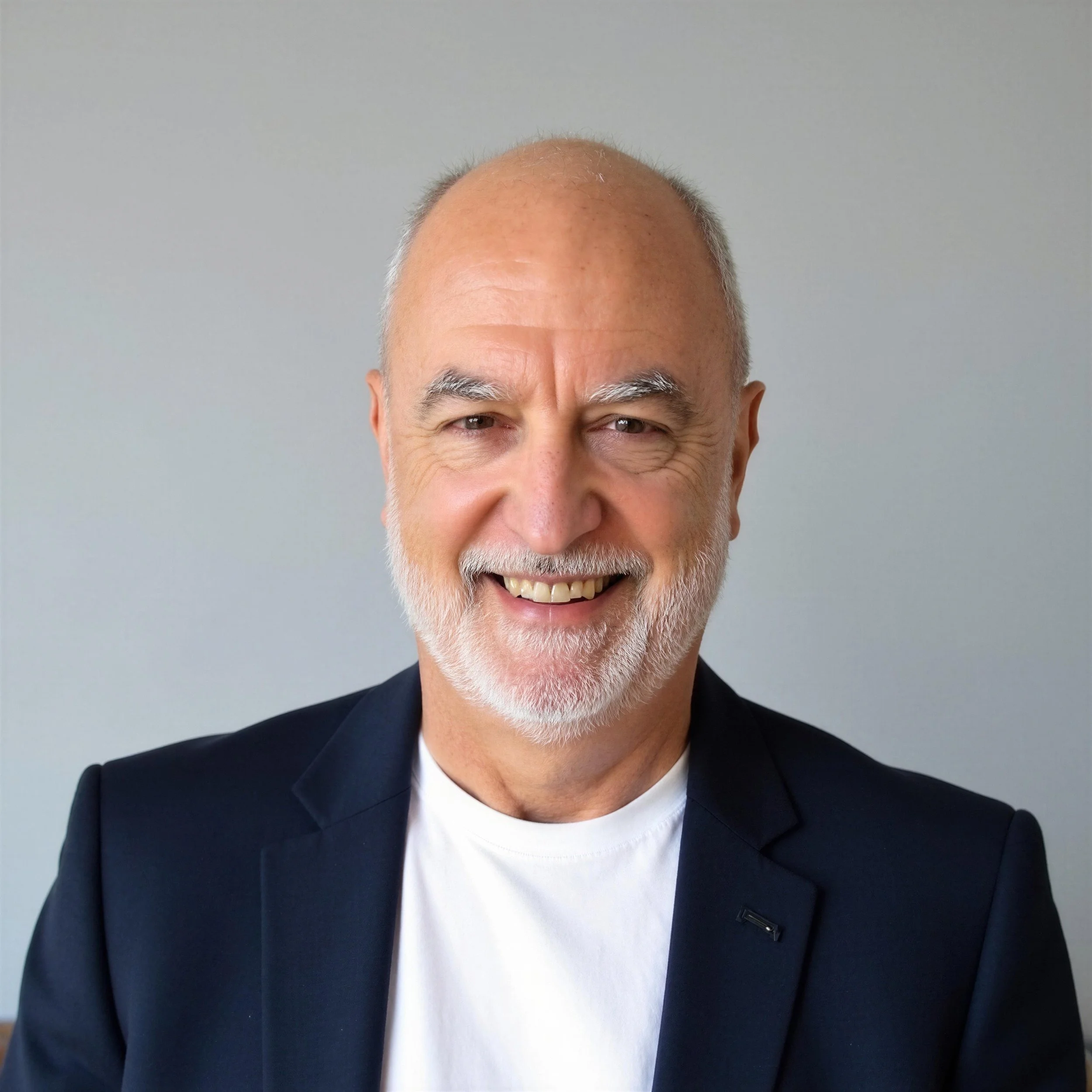 A smiling middle-aged man with a beard, wearing a dark suit, white shirt, and a striped tie.