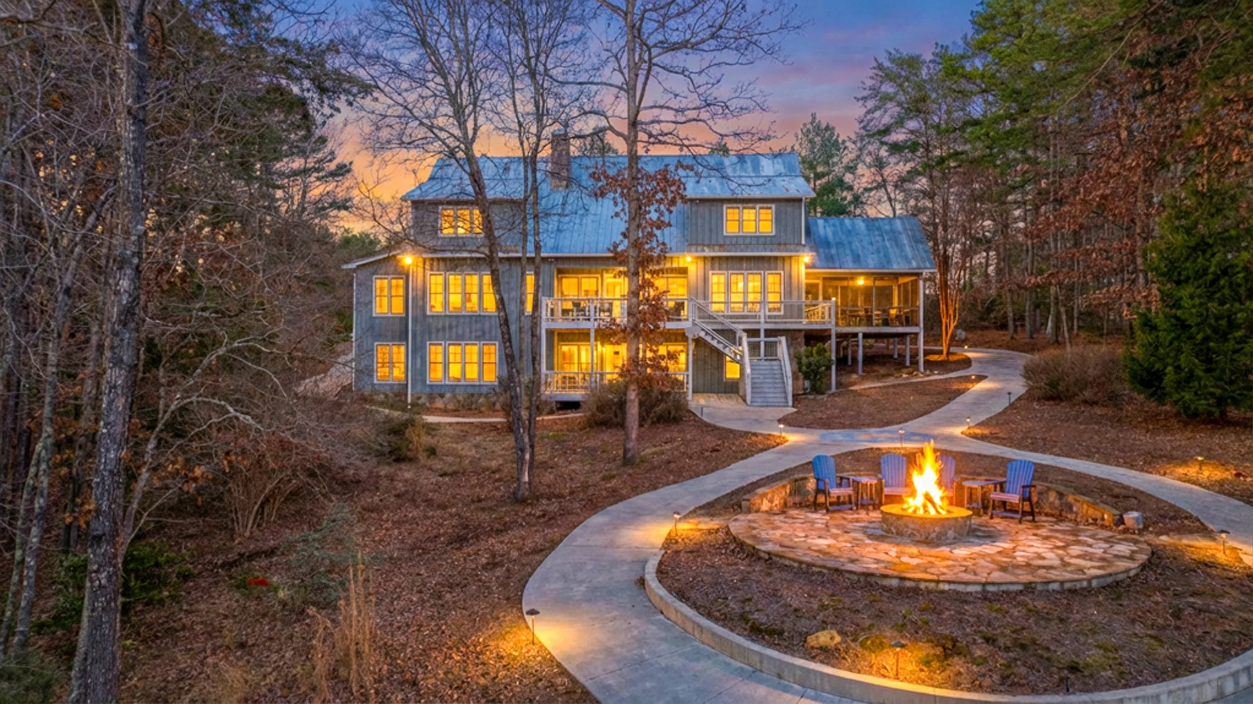 Virtual Dusk image of the rear elevation of a Luxury Lakefront home with virtual fire in the fire pit