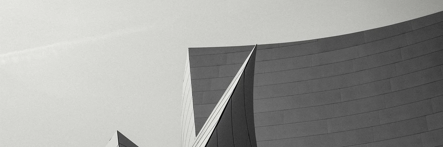 Black and white photo of modern architectural building with angular, curved, and pointed sections.