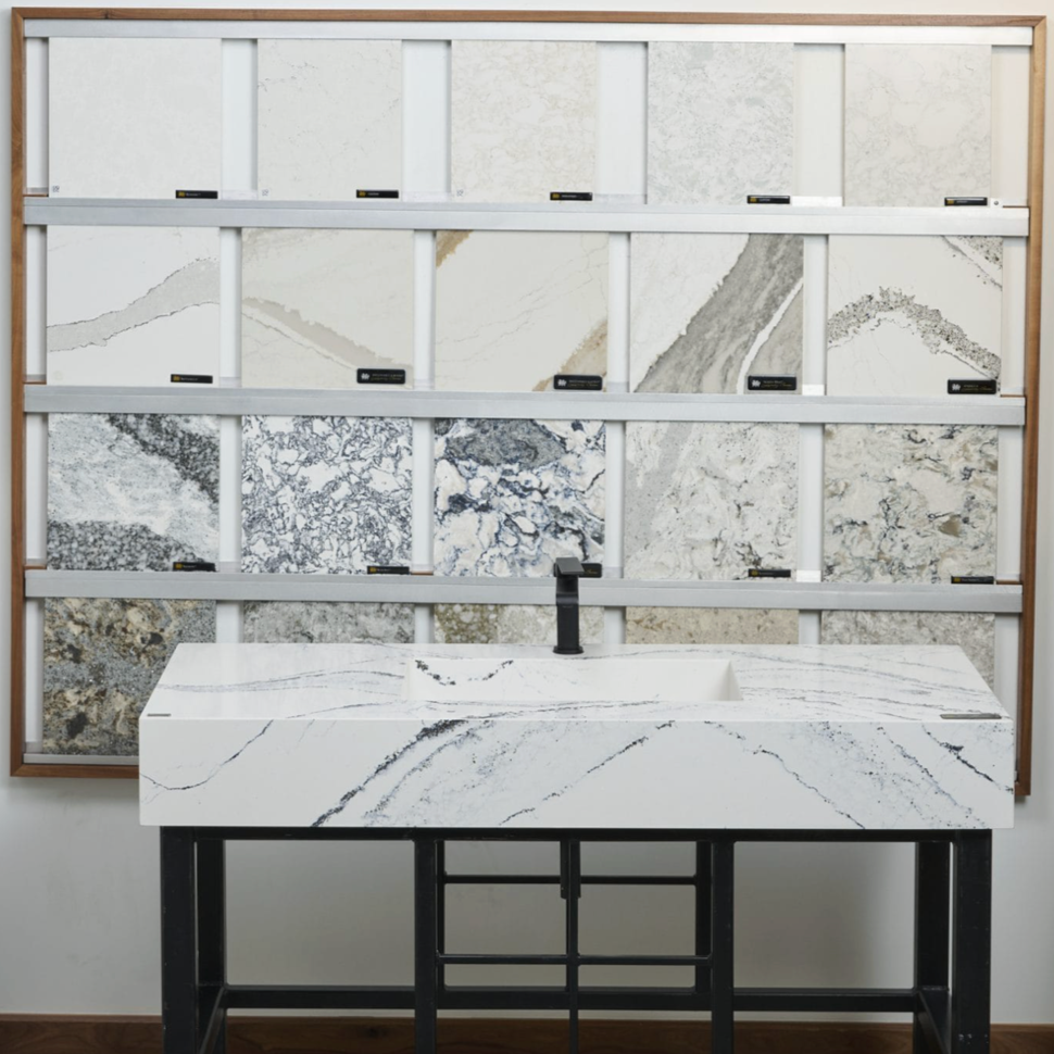 Display of various marble samples behind a marble sink with a black faucet.