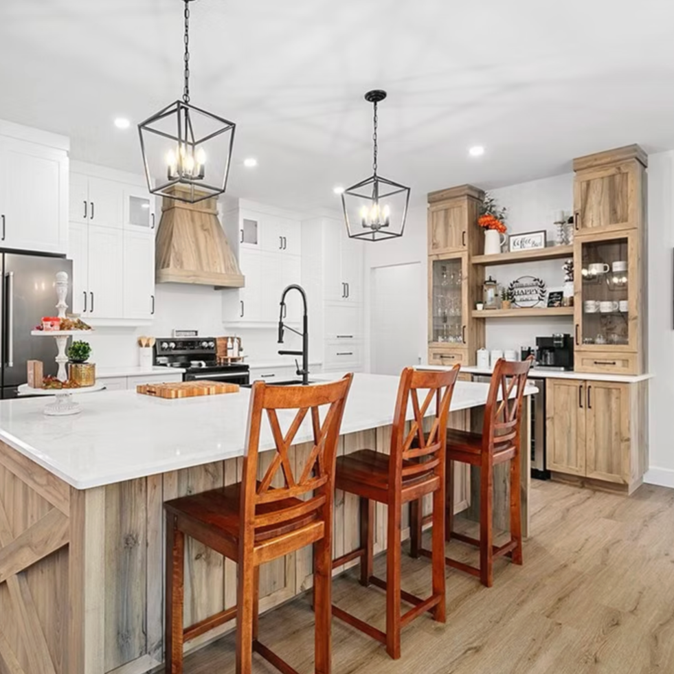 Modern kitchen with white cabinets, wooden accents, a large island with a white countertop, three wooden barstools, black fixtures, and open shelving with decorative items.