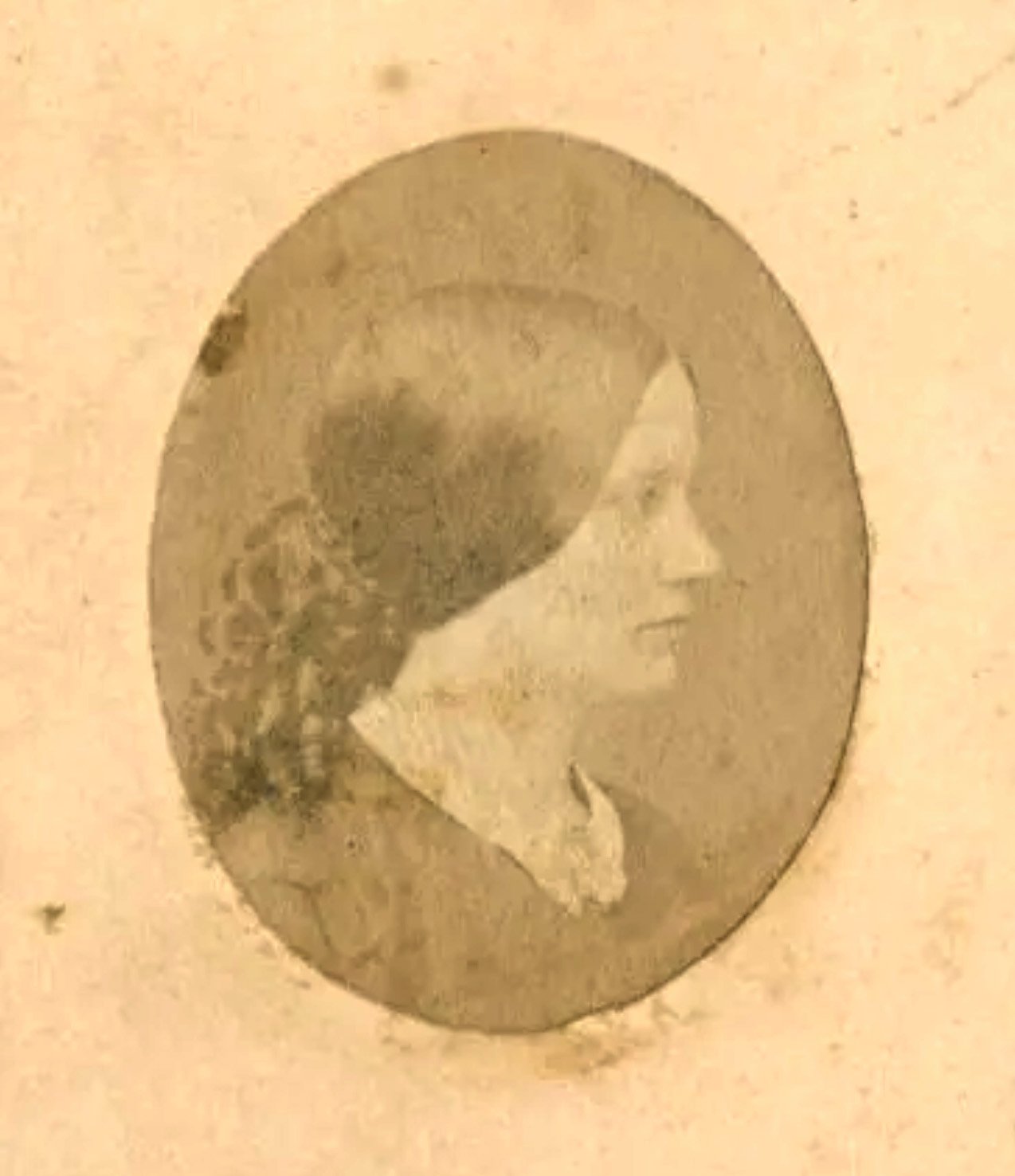 Close-up of a vintage coin featuring a profile of a woman with short hair, wearing glasses, within a circular border.